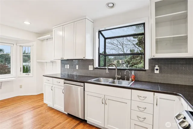 a kitchen with granite countertop white cabinets and window