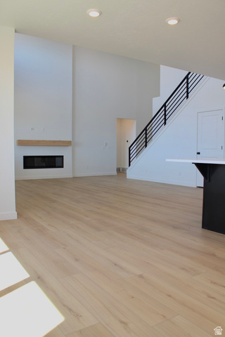 2613 Scarlet Road, Unit 258 Eagle Mountain, UT 84005 - Photo 11 of 32 Spacious living area featuring wood-finish flooring, a contemporary fireplace with a wood mantle, and a modern staircase with black railings
