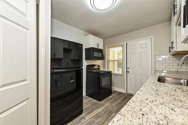 a kitchen with granite countertop stainless steel appliances a sink stove top oven and refrigerator