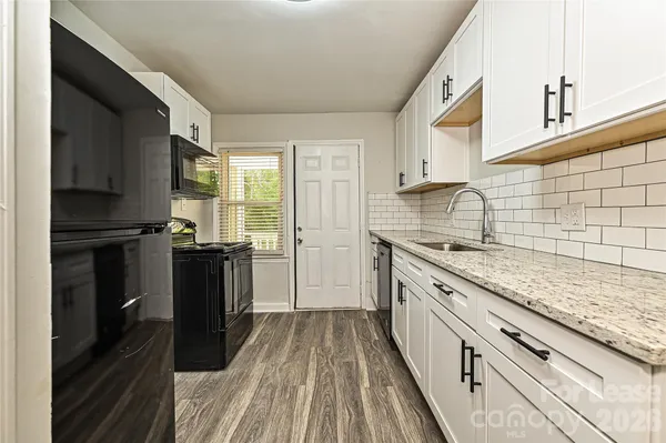 a kitchen with granite countertop white cabinets and sink
