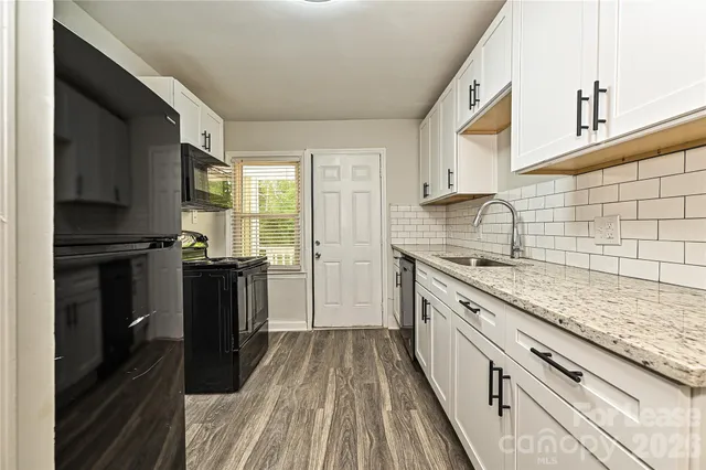 a kitchen with granite countertop white cabinets and sink