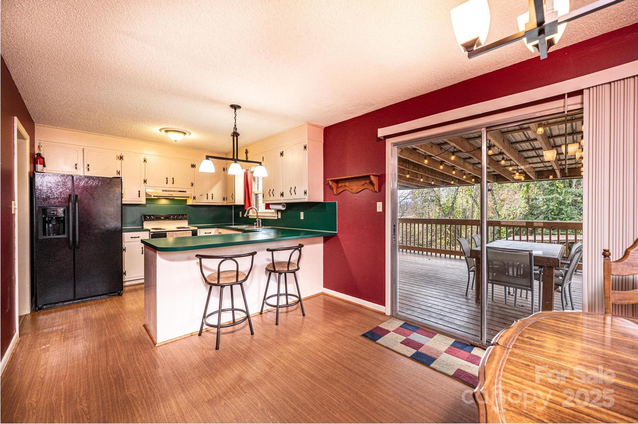 2570 Raintree Street Connelly Springs, NC 28612 - Photo 8 of 37 a kitchen with stainless steel appliances granite countertop a refrigerator a stove top oven and a dining table with wooden floor