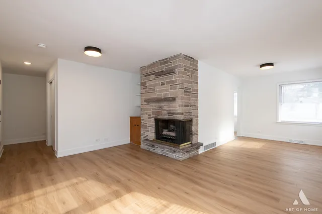 an empty room with wooden floor fireplace and window