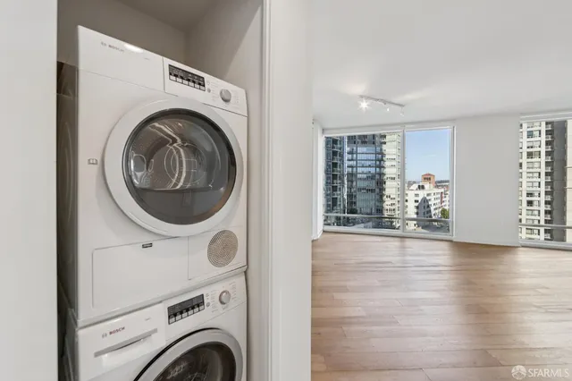 a view of balcony with a couple of cars parked in front of buildings
