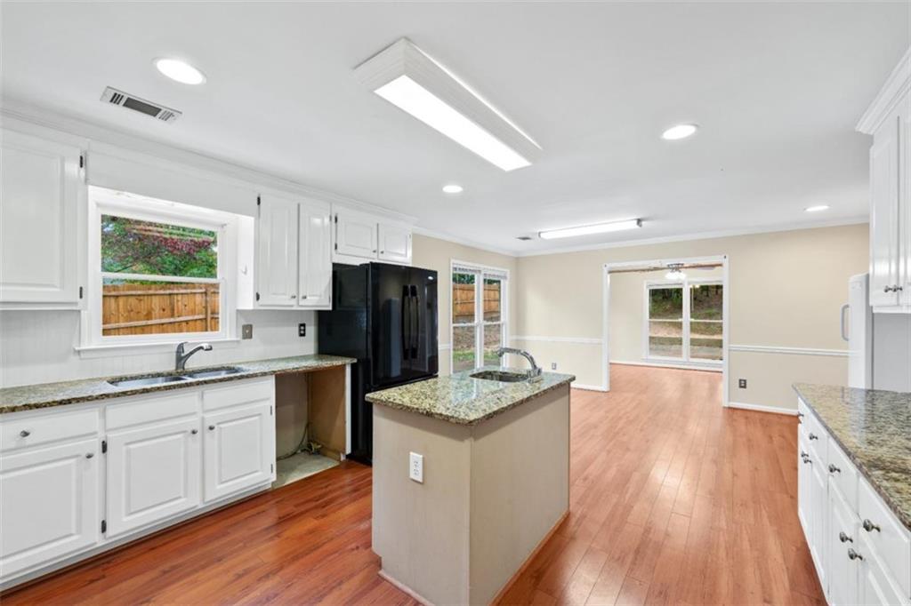 2985 Ashton Pointe Circle Dacula, GA 30019 - Photo 19 of 47 a large kitchen with kitchen island granite countertop a stove a sink a refrigerator and white cabinets with wooden floor