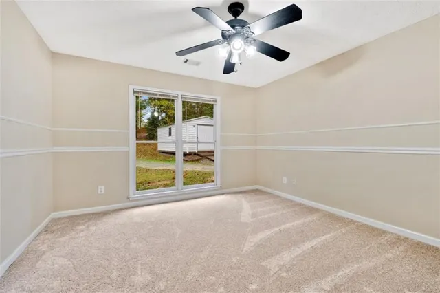 an empty room with chandelier fan and windows