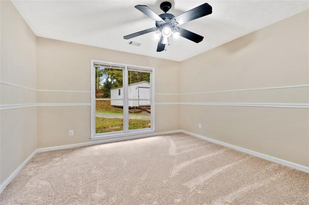 2985 Ashton Pointe Circle Dacula, GA 30019 - Photo 26 of 47 an empty room with chandelier fan and windows