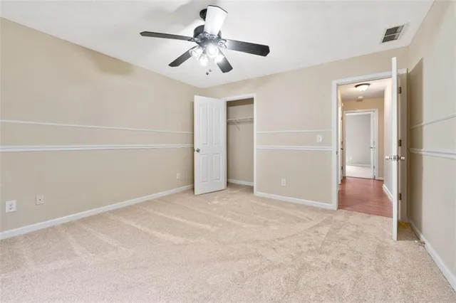 an empty room with closet and a ceiling fan