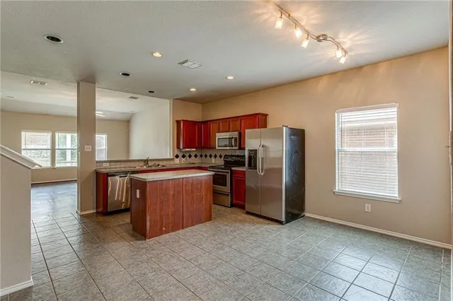 a kitchen with stainless steel appliances granite countertop a refrigerator and a stove top oven