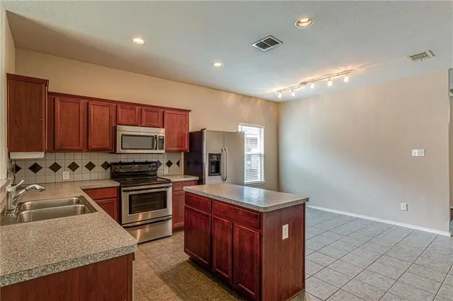 a kitchen with stainless steel appliances granite countertop a sink stove microwave and refrigerator