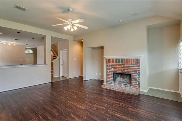 an empty room with wooden floor fireplace and a window