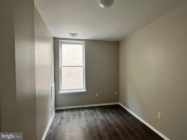 an empty room with wooden floor and window