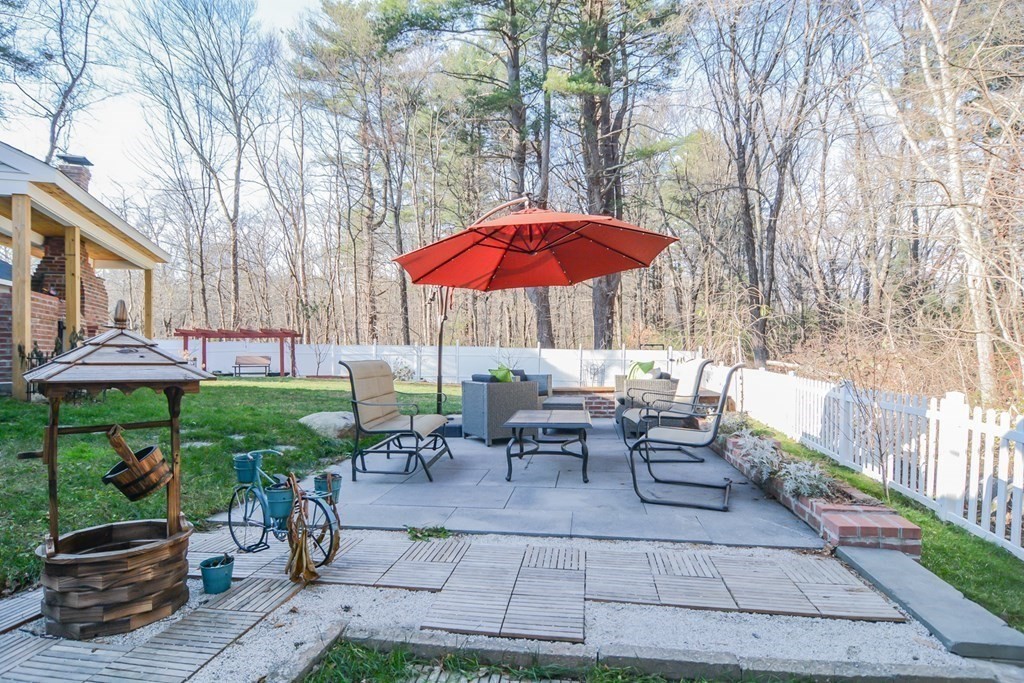 94 West Street Medway, MA 02053 - Photo 28 of 41 a view of a patio with table and chairs under an umbrella with large trees