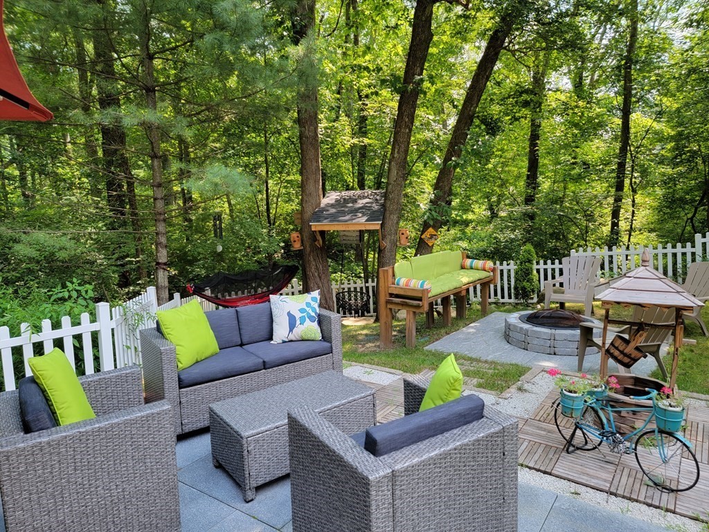 94 West Street Medway, MA 02053 - Photo 32 of 41 a view of a patio with couches table and chairs under an umbrella with large trees