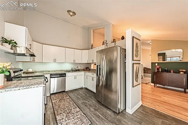 a kitchen with stainless steel appliances granite countertop a refrigerator a stove and a wooden floors