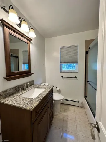 a bathroom with a granite countertop sink toilet and mirror