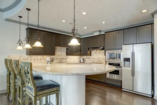 a kitchen with kitchen island granite countertop lots of counter top space and refrigerator