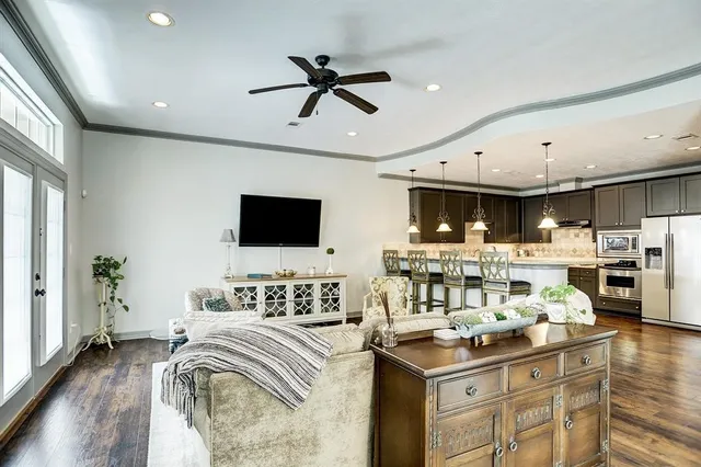 a living room with stainless steel appliances furniture and a flat screen tv