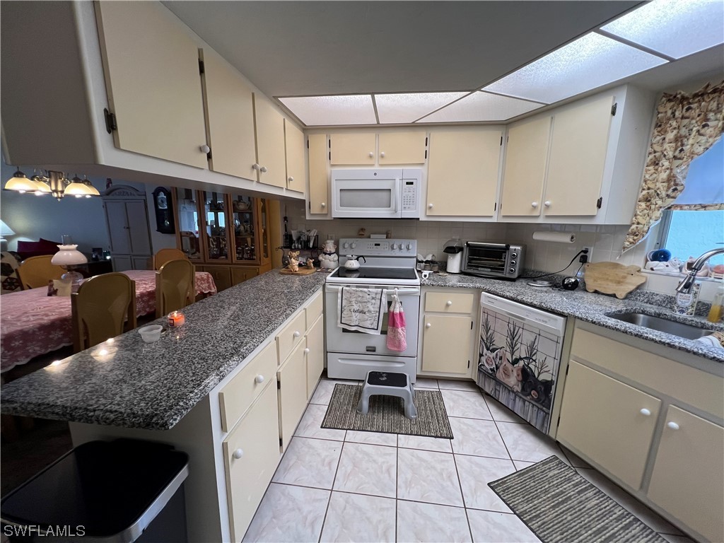 3 Regency Court Lehigh Acres, FL 33936 - Photo 11 of 27 a kitchen with granite countertop a sink stove and cabinets