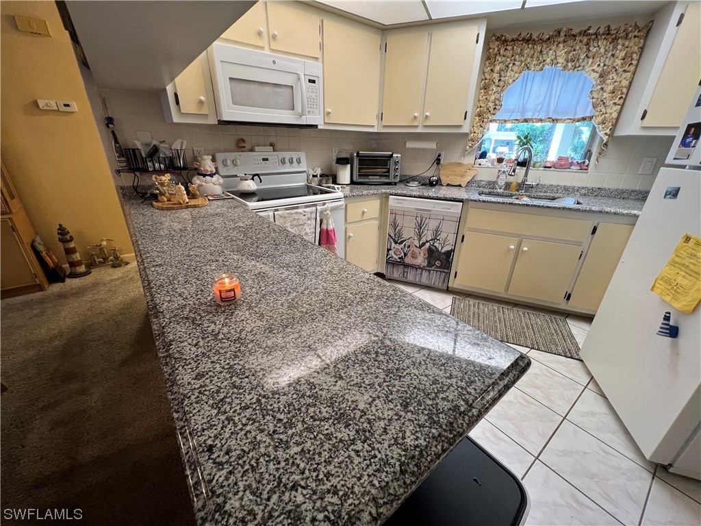 3 Regency Court Lehigh Acres, FL 33936 - Photo 8 of 27 a kitchen with stainless steel appliances granite countertop a sink stove and cabinets