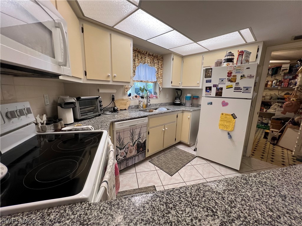 3 Regency Court Lehigh Acres, FL 33936 - Photo 9 of 27 a kitchen with stainless steel appliances granite countertop a stove a sink and a microwave