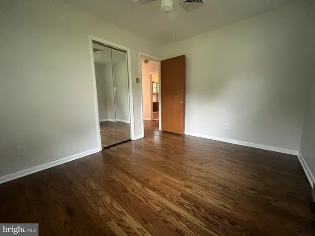 a view of an empty room with wooden floor and closet