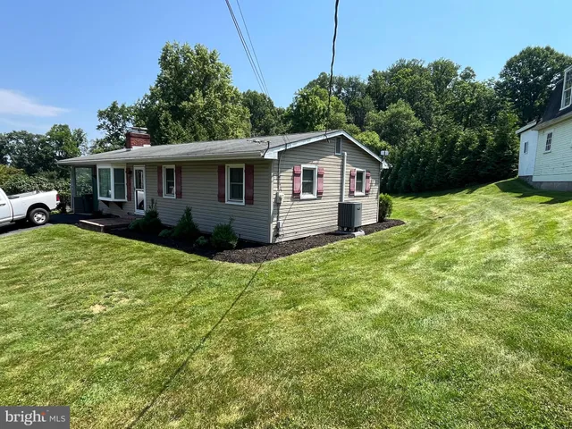 a view of a house with a big yard and large trees