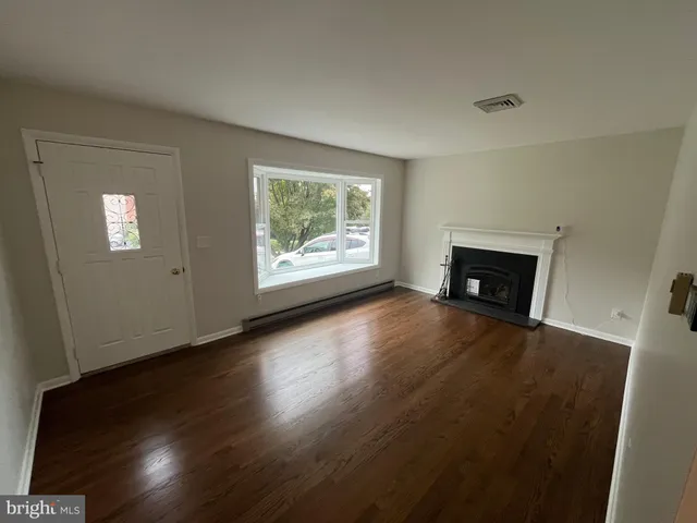 an empty room with windows fireplace and wooden table