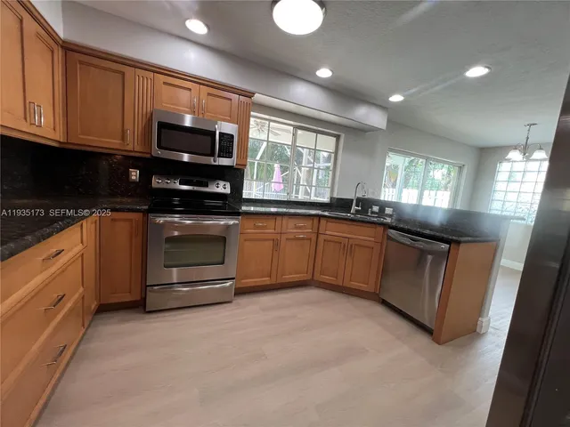 a kitchen with stainless steel appliances granite countertop a stove sink microwave and window