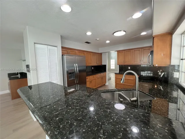 a kitchen with granite countertop a refrigerator and a sink