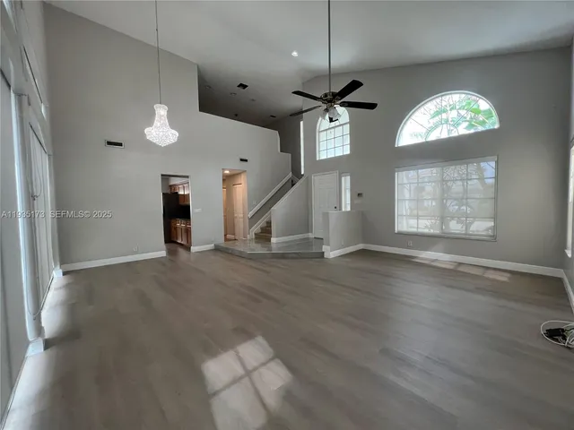 an empty room with wooden floor chandelier and entryway