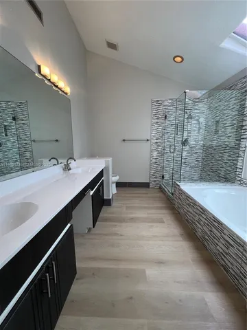 a bathroom with a double vanity sink a toilet a mirror and bathtub