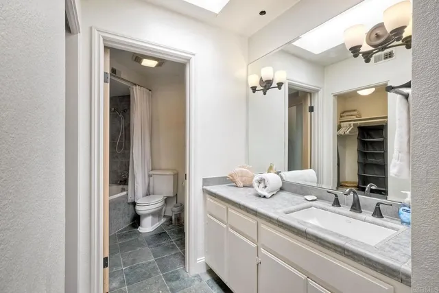 a bathroom with a granite countertop sink mirror and toilet