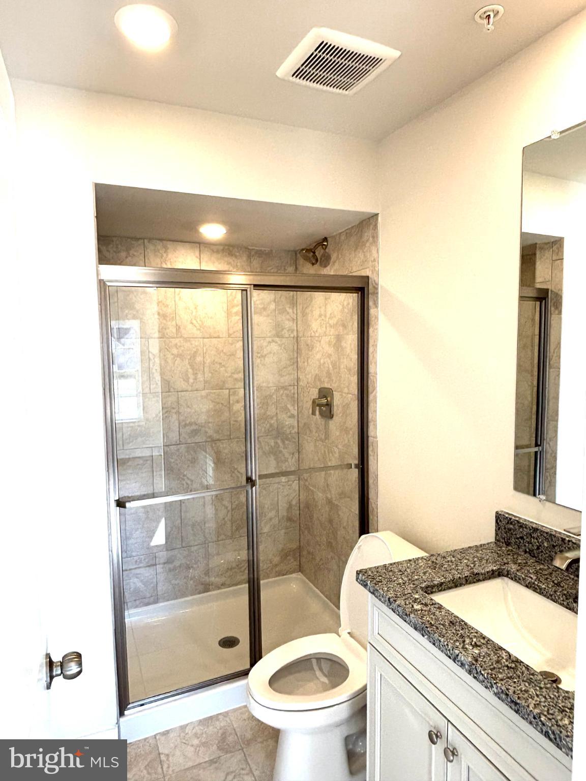 7700 Johnnycake Road Windsor Mill, MD 21244 - Photo 11 of 17 a bathroom with a granite countertop sink a toilet a mirror and shower