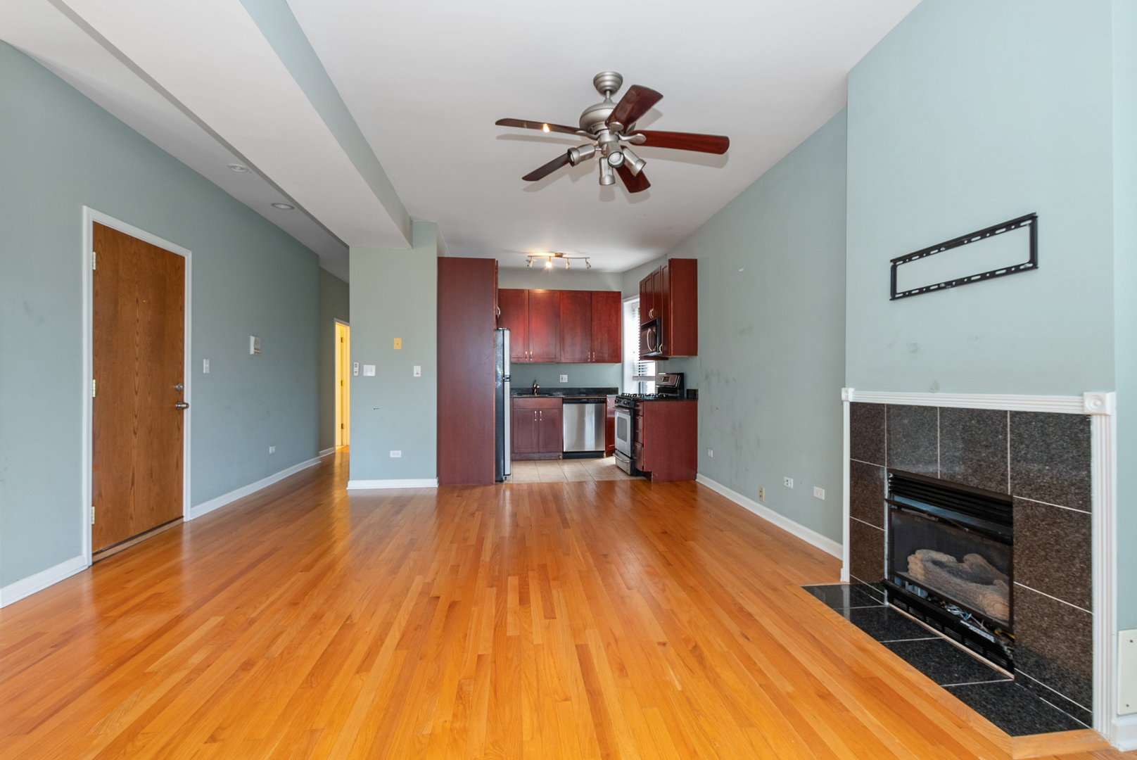6603 South Kimbark Avenue, Unit 3 Chicago, IL 60637 - Photo 5 of 16 a view of a livingroom with a fireplace a ceiling fan and wooden floor