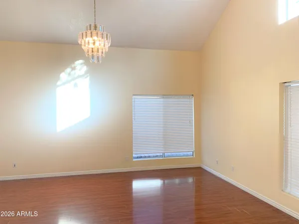 an empty room with wooden floor chandelier and window