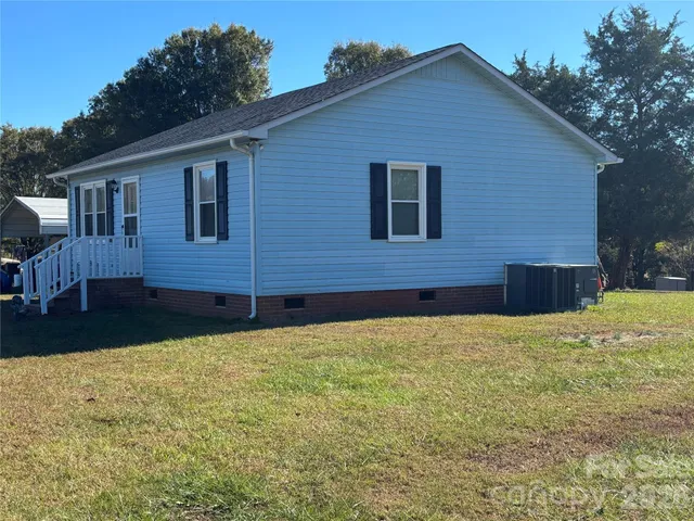 a brick house next to a yard with a large tree