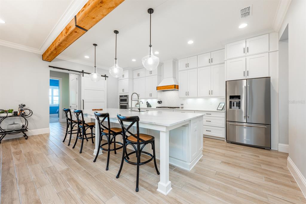 9014 Morgana Court Winter Garden, FL 34787 - Photo 11 of 55 a kitchen with granite countertop a refrigerator a stove a sink and white cabinets with wooden floor