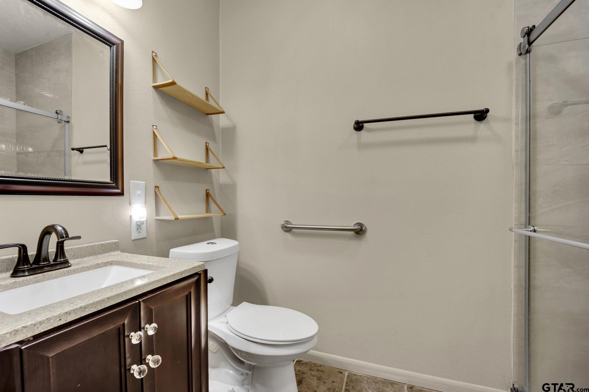 3204 West Tulsa Street Tyler, TX 75702 - Photo 15 of 24 a bathroom with a granite countertop sink toilet and a mirror