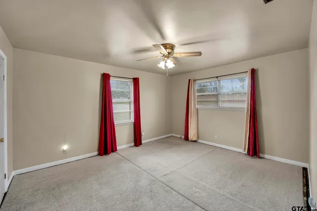 an empty room with a ceiling fan and a window