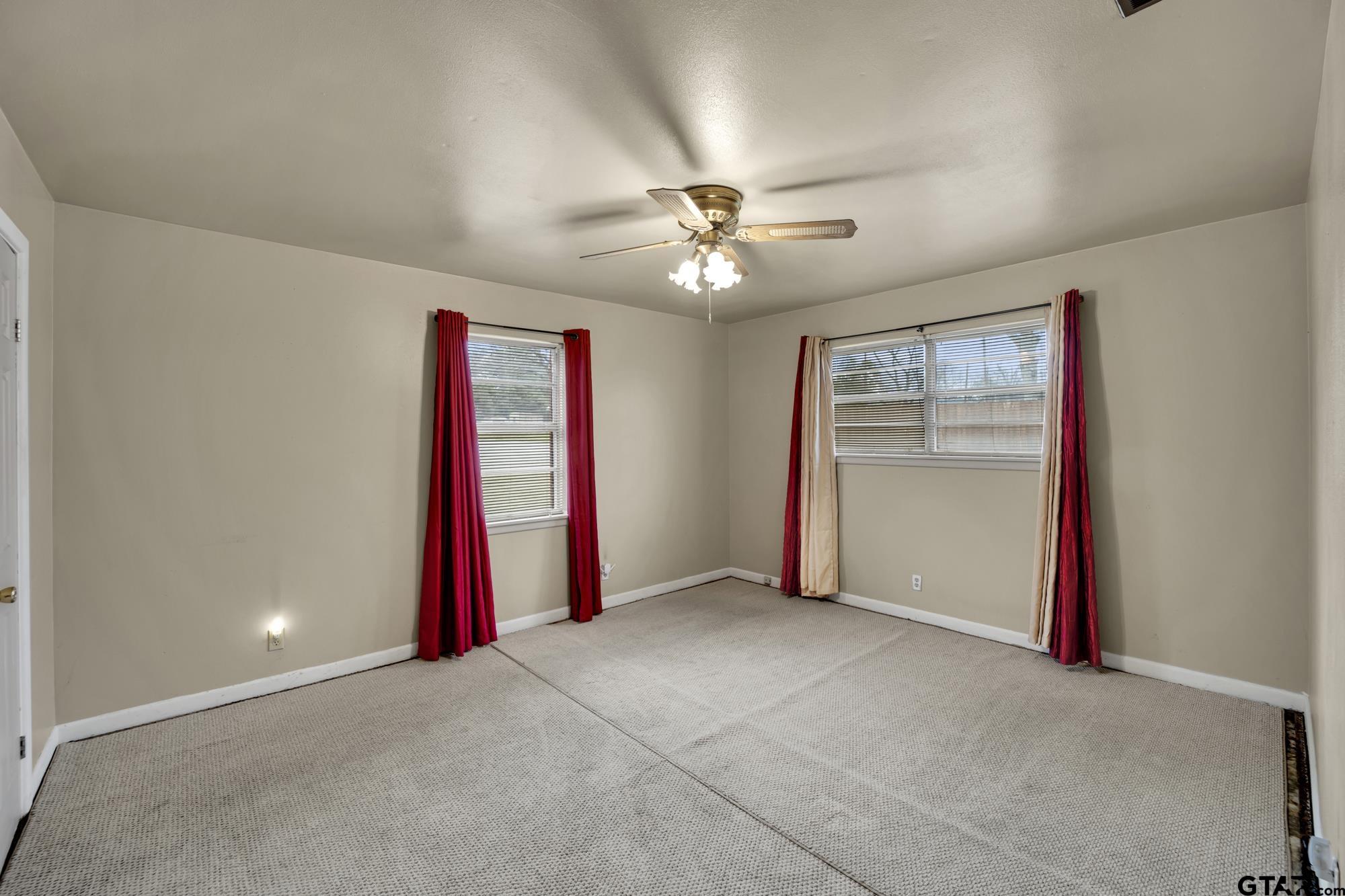 3204 West Tulsa Street Tyler, TX 75702 - Photo 18 of 24 an empty room with a ceiling fan and a window
