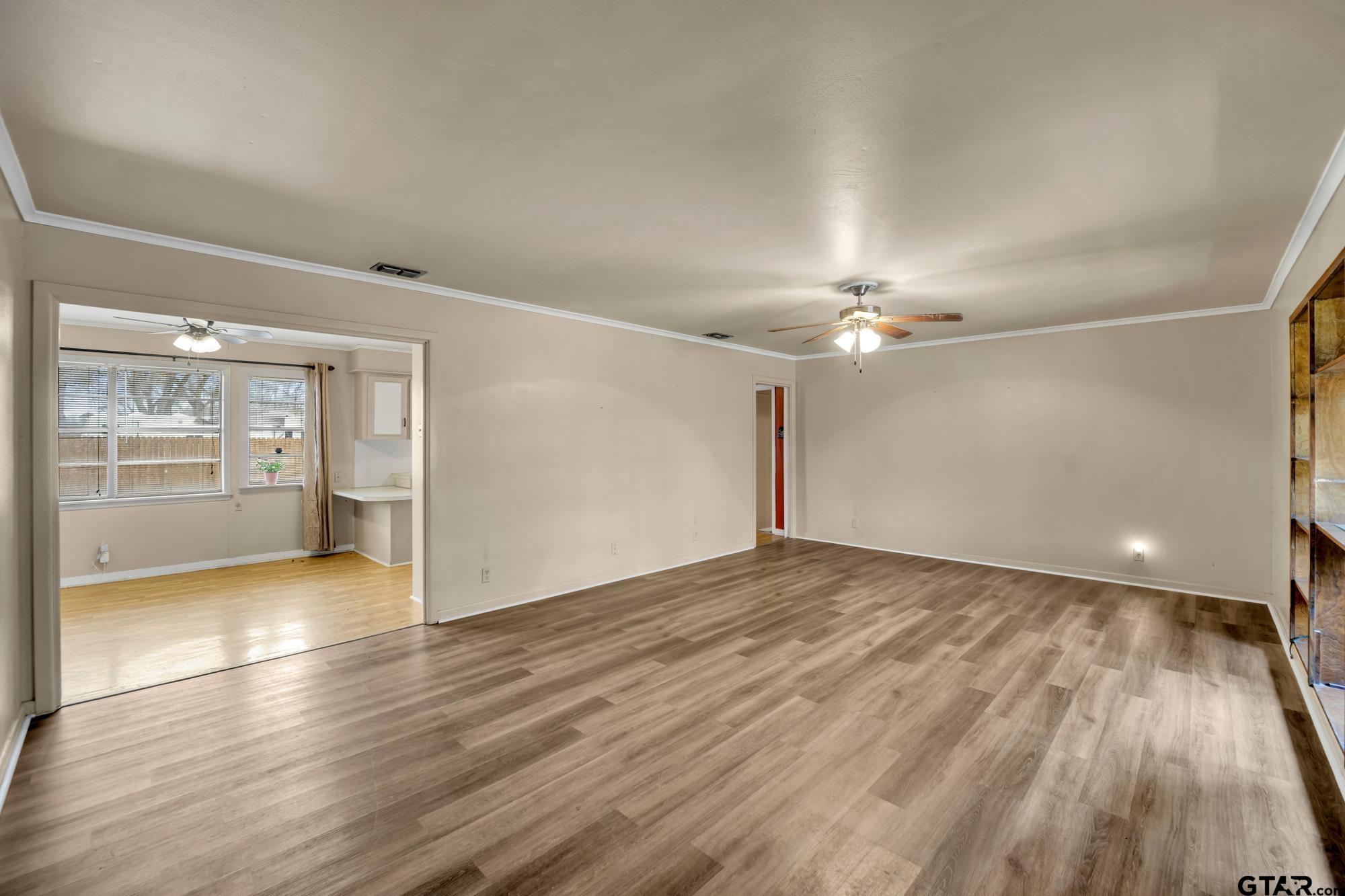 3204 West Tulsa Street Tyler, TX 75702 - Photo 6 of 24 an empty room with wooden floor chandelier fan and windows