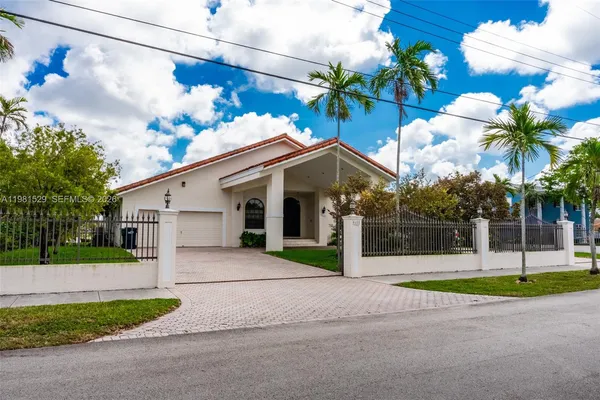 a view of a house with a yard and palm trees