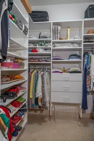 a view of walk in closet with clothes and shoes
