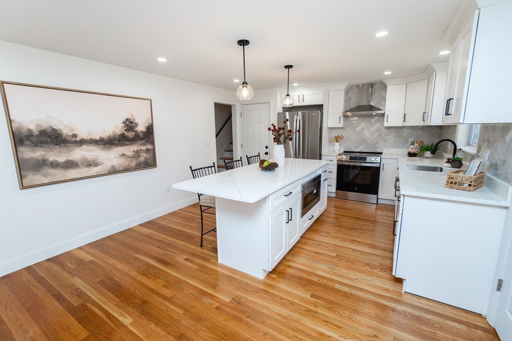 72 Outlook Road Wakefield, MA 01880 - Photo 2 of 42 a large white kitchen with stainless steel appliances granite countertop a stove oven a refrigerator white cabinets and wooden floor