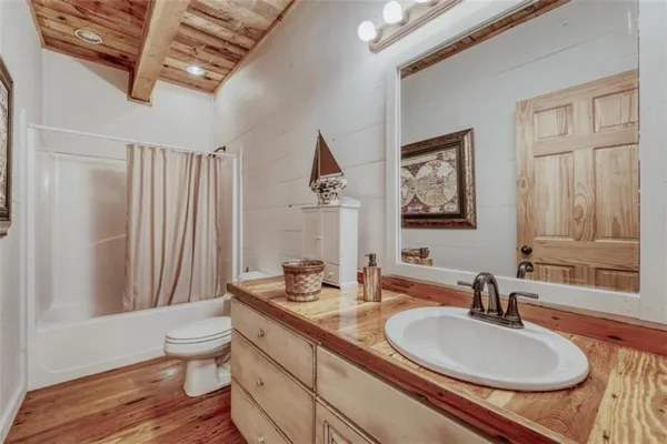 a bathroom with a granite countertop sink a toilet a mirror and shower curtain