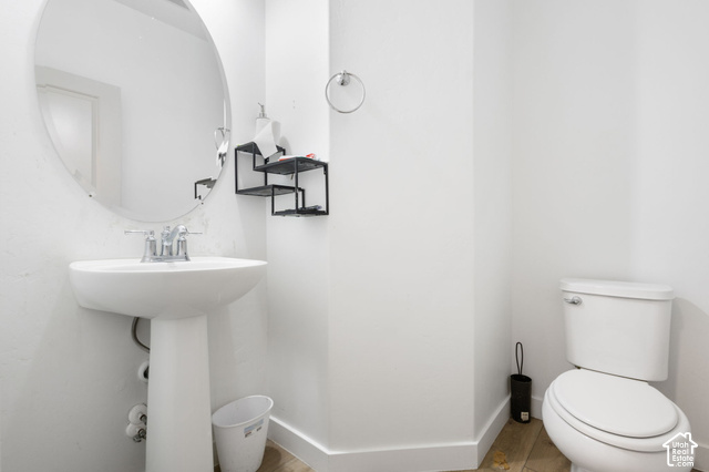 7723 Conger Road Magna, UT 84044 - Photo 5 of 24 White pedestal sink with chrome faucet, circular mirror, and wood-finish flooring