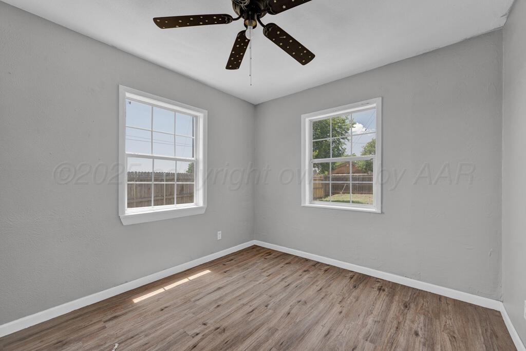 4360 South Polk Street Amarillo, TX 79110 - Photo 12 of 20 an empty room with wooden floor ceiling fan and windows