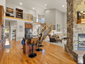 514 North Olympic Way Midway, UT 84049 - Photo 4 of 30 Open-concept interior featuring wood-finish flooring, a stone-clad fireplace, and a kitchen island with seating