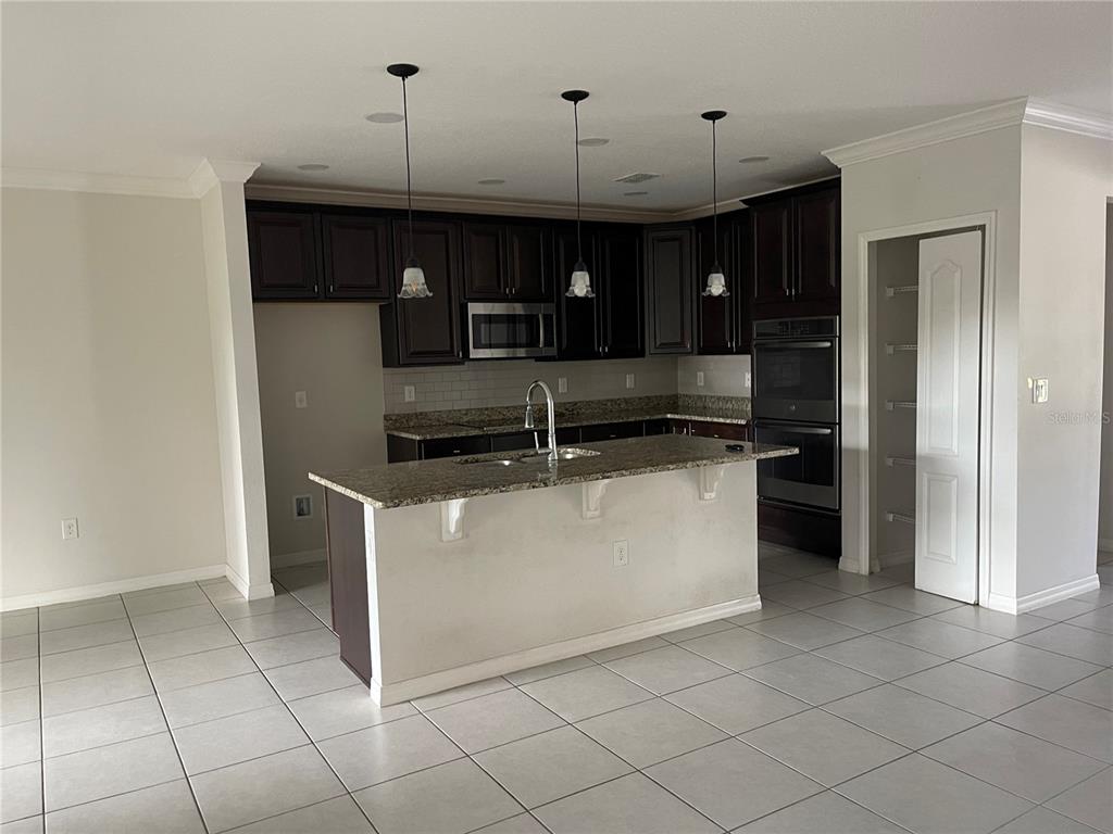 1312 Ralph Poe Drive Apopka, FL 32703 - Photo 8 of 14 a kitchen with kitchen island granite countertop a refrigerator and a stove top oven